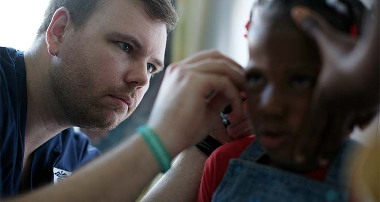 medical profesional checks child's ear